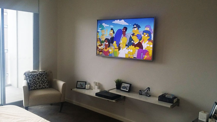 TV installation design ideas with floating shelves mounted below.